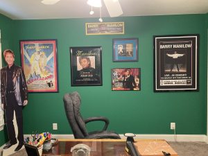 My craft room has green walls. A life-size cardboard figure of Barry Manilow stands on the left. Framed posters are on the wall, left to right: Copacabana (Barry's movie in which he starred), his concert at the Las Vegas Mirage, his single The One That Got Away, his Wembley concert with my ticket stubs, his Singing With The Big Bands album, and the 1994 Hamburg tour poster.